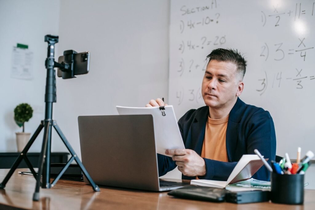 Teacher running an online class with a laptop and camera