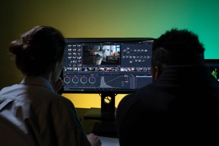 Two editors working on video with dual monitors